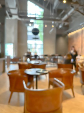 Modern bir kahve dükkanının bulanık görüntüsü, zarif dekore edilmiş ve sıcak, müşteriler mutlu bir şekilde çalışıyor ve sohbet ediyorlar..