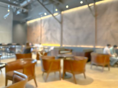 Modern bir kahve dükkanının bulanık görüntüsü, zarif dekore edilmiş ve sıcak, müşteriler mutlu bir şekilde çalışıyor ve sohbet ediyorlar..