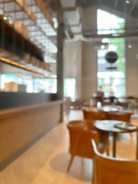 Modern bir kahve dükkanının bulanık görüntüsü, zarif dekore edilmiş ve sıcak, müşteriler mutlu bir şekilde çalışıyor ve sohbet ediyorlar..