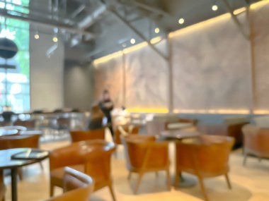 Modern bir kahve dükkanının bulanık görüntüsü, zarif dekore edilmiş ve sıcak, müşteriler mutlu bir şekilde çalışıyor ve sohbet ediyorlar..