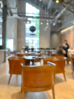 Modern bir kahve dükkanının bulanık görüntüsü, zarif dekore edilmiş ve sıcak, müşteriler mutlu bir şekilde çalışıyor ve sohbet ediyorlar..