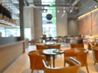 Modern bir kahve dükkanının bulanık görüntüsü, zarif dekore edilmiş ve sıcak, müşteriler mutlu bir şekilde çalışıyor ve sohbet ediyorlar..