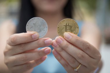 Elinde Bitcoin dijital para ve arka planı bulanık kripto para tutan güzel bir kadın. Kaşsız Toplum kavramı Web Sanal Para Madenciliği.