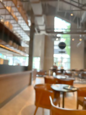 Modern bir kahve dükkanının bulanık görüntüsü, zarif dekore edilmiş ve sıcak, müşteriler mutlu bir şekilde çalışıyor ve sohbet ediyorlar..