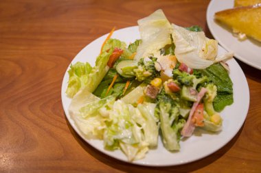 Servis masasında seramik tabakta sebze salatası karışımı.