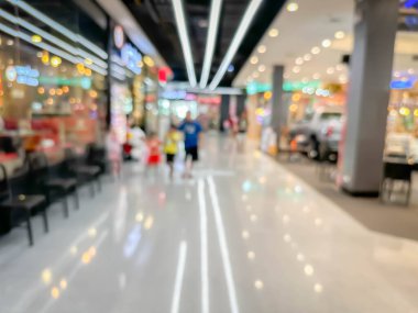 Modern bir şekilde dekore edilmiş önde gelen bir alışveriş merkezinde yürüyen ve alışveriş yapan insanların bulanık görüntüsü