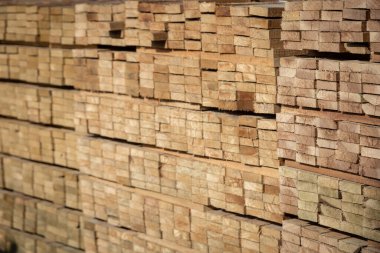 Kereste deposunda istiflenmiş ahşap kalaslar, çeşitli gölgeler ve dokular, düzenli bir şekilde düzenlenmiş..