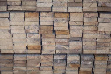 Kereste deposunda istiflenmiş ahşap kalaslar, çeşitli gölgeler ve dokular, düzenli bir şekilde düzenlenmiş..