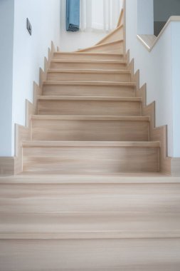 Modern, açık renkli ahşap bir merdiven çağdaş bir evde, temiz çizgiler ve minimalist tasarım sergiliyor..