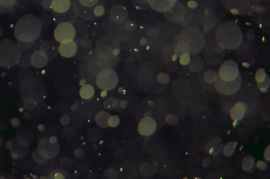 Koyu bir arkaplanda farklı boyut ve renklerde odaklanmış bokeh ışıkları.