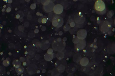 Koyu bir arkaplanda farklı boyut ve renklerde odaklanmış bokeh ışıkları.