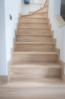 Modern, açık renkli ahşap bir merdiven çağdaş bir evde, temiz çizgiler ve minimalist tasarım sergiliyor..
