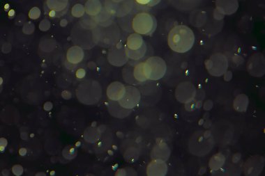 Koyu bir arkaplanda farklı boyut ve renklerde odaklanmış bokeh ışıkları.