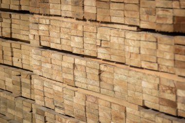 Kereste deposunda istiflenmiş ahşap kalaslar, çeşitli gölgeler ve dokular, düzenli bir şekilde düzenlenmiş..