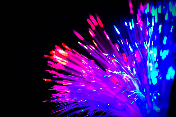 Close up of blurred light fiber optics for communication technology network on black background