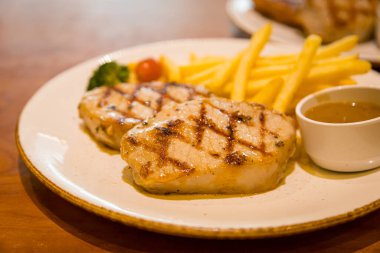 Kızarmış domuz bifteği, yanında patates kızartması ve sebze.