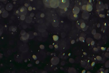 Koyu bir arkaplanda farklı boyut ve renklerde odaklanmış bokeh ışıkları.