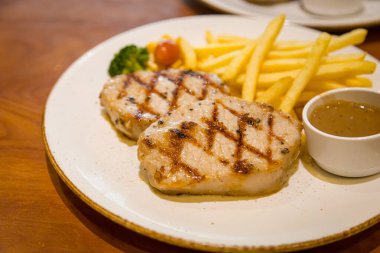 Kızarmış domuz bifteği, yanında patates kızartması ve sebze.