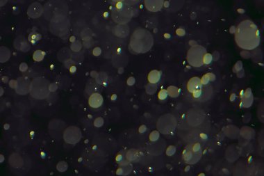 Koyu bir arkaplanda farklı boyut ve renklerde odaklanmış bokeh ışıkları.