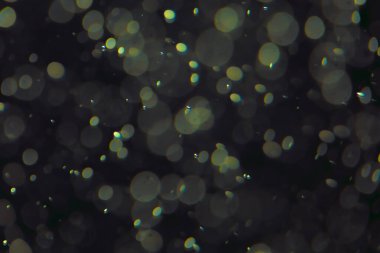 Koyu bir arkaplanda farklı boyut ve renklerde odaklanmış bokeh ışıkları.