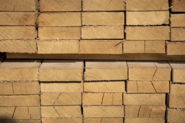 Kereste deposunda istiflenmiş ahşap kalaslar, çeşitli gölgeler ve dokular, düzenli bir şekilde düzenlenmiş..