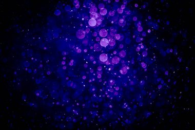 Bir fincan kahve ve şişeyle ön planda ahşap bir masa bulunan bulanık, modern kafe salonu.