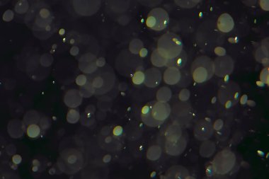 Koyu bir arkaplanda farklı boyut ve renklerde odaklanmış bokeh ışıkları.