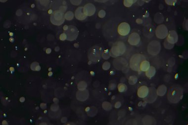 Koyu bir arkaplanda farklı boyut ve renklerde odaklanmış bokeh ışıkları.