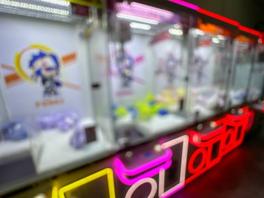 Pembe pelüş oyuncaklarla dolu renkli bir pençe makinesi oyuncuları eğlenceli bir oyun salonunda şanslarını denemeye davet ediyor..