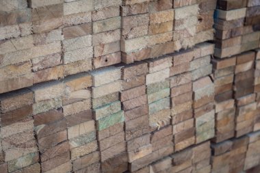 Kereste deposunda istiflenmiş ahşap kalaslar, çeşitli gölgeler ve dokular, düzenli bir şekilde düzenlenmiş..