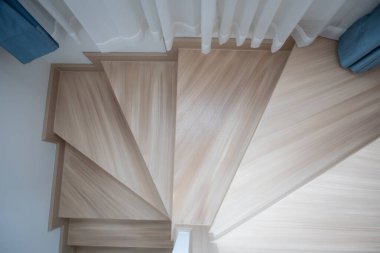 Modern, açık renkli ahşap bir merdiven çağdaş bir evde, temiz çizgiler ve minimalist tasarım sergiliyor..