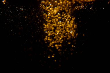 Soyut bulanık altın bokeh ışıkları koyu bir arkaplan karşısında dramatik ve şenlikli bir atmosfer yaratır.