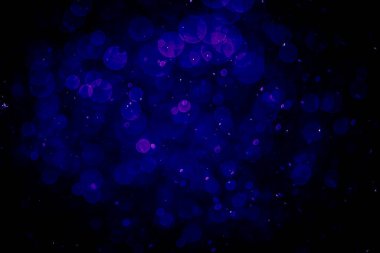 Bir fincan kahve ve şişeyle ön planda ahşap bir masa bulunan bulanık, modern kafe salonu.