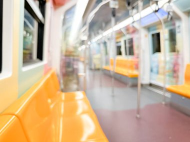 Parlak sarı koltukları ve paslanmaz çelik direkleriyle metro içi boş bir metro manzarası. Modern tren vagonu iyi ışıklandırılmış, üst kulpları ve pürüzsüz, temiz zeminleri var, hareket halindeki toplu taşımayı öneriyor..