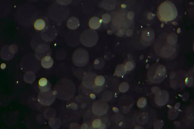 Koyu bir arkaplanda farklı boyut ve renklerde odaklanmış bokeh ışıkları.