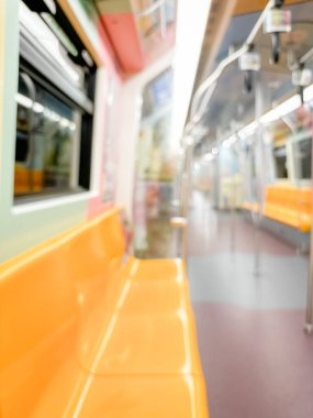 Parlak sarı koltukları ve paslanmaz çelik direkleriyle metro içi boş bir metro manzarası. Modern tren vagonu iyi ışıklandırılmış, üst kulpları ve pürüzsüz, temiz zeminleri var, hareket halindeki toplu taşımayı öneriyor..