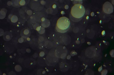 Koyu bir arkaplanda farklı boyut ve renklerde odaklanmış bokeh ışıkları.