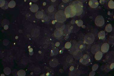 Koyu bir arkaplanda farklı boyut ve renklerde odaklanmış bokeh ışıkları.