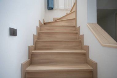Modern, açık renkli ahşap bir merdiven çağdaş bir evde, temiz çizgiler ve minimalist tasarım sergiliyor..