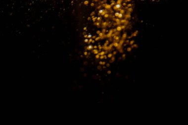 Soyut bulanık altın bokeh ışıkları koyu bir arkaplan karşısında dramatik ve şenlikli bir atmosfer yaratır.