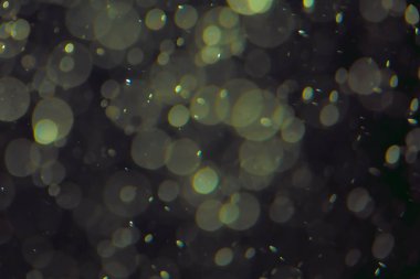 Koyu bir arkaplanda farklı boyut ve renklerde odaklanmış bokeh ışıkları.