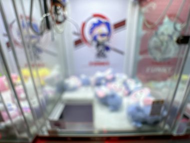 Pembe pelüş oyuncaklarla dolu renkli bir pençe makinesi oyuncuları eğlenceli bir oyun salonunda şanslarını denemeye davet ediyor..