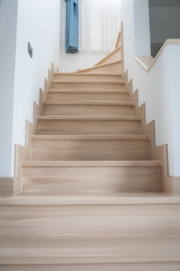 Modern, açık renkli ahşap bir merdiven çağdaş bir evde, temiz çizgiler ve minimalist tasarım sergiliyor..