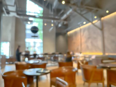 Ahşap sandalyeli, masalı, sıcak ışıklandırmalı ve büyük pencereli modern bir kafe.