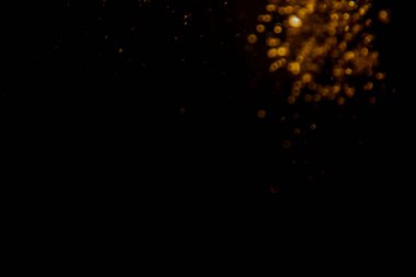 Soyut bulanık altın bokeh ışıkları koyu bir arkaplan karşısında dramatik ve şenlikli bir atmosfer yaratır.