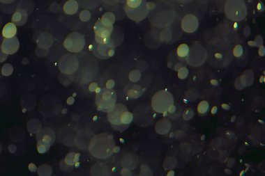 Koyu bir arkaplanda farklı boyut ve renklerde odaklanmış bokeh ışıkları.