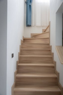 Modern, açık renkli ahşap bir merdiven çağdaş bir evde, temiz çizgiler ve minimalist tasarım sergiliyor..