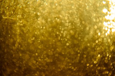 Soyut bulanık altın parıltı dokusu ışıltılı bokeh ışıklarıyla şenlikli bir zemin oluşturuyor.