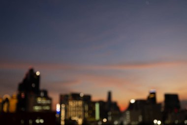 Renkli bokeh ışıkları ve alacakaranlık gökyüzü ile bulanık şehir manzarası soyut şehir atmosferini ve akşam atmosferini vurguluyor.