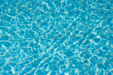 Işıldayan mavi su yüzeyine yakın çekim. Karmaşık ışık yansımaları dinamik dalgalanmalar yaratıyor. Ferahlatıcı ve yazlık bir ortam yaratıyor..